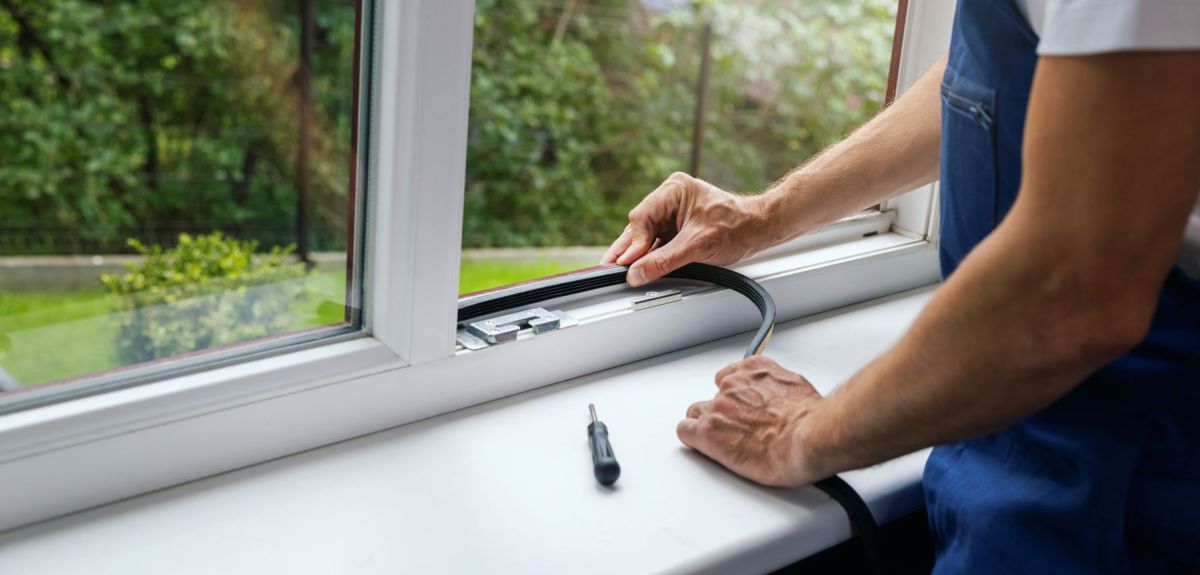 Hands fitting a rubber weather seal into a window frame
